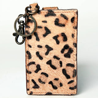 The Leopard Card Holder by American Darling is a rectangular keychain accessory with a chic leopard print design, perfect for the fashionista. Featuring a fabric loop and metallic hook clasp for easy attachment to your purse, this holder showcases various black spots on a light brown background, mimicking a leopard's fur pattern.