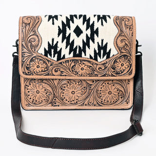 The Western Tooled Messenger Purse by Western Edge Boutique showcases a sophisticated design with black and white geometric patterns inspired by Aztec motifs on the flap, along with intricately tooled floral engravings on the tan leather. It includes a dark brown shoulder strap that enhances its elegance.