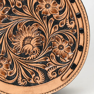 Close-up of an intricately tooled leather design on the Bliss Horseshoe Tooled Canteen Purse by American Darling, showcasing detailed floral and leaf patterns. The high-quality genuine leather displays a blend of light and dark hues, with the flowers and leaves appearing in a generally lighter tan color against a darker background.