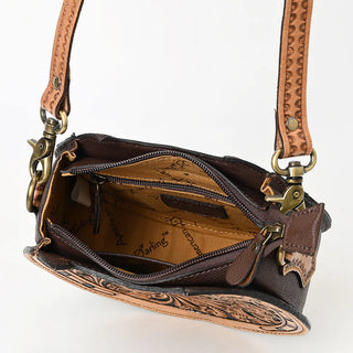 A close-up of the Bliss Horseshoe Tooled Canteen Purse by American Darling showcases its intricate floral tooling on brown genuine leather. The purse is open, revealing a zippered pocket and a beige fabric lining with a printed logo. Featuring brass hardware and an adjustable strap adorned with decorative patterns, this handbag exemplifies fine craftsmanship.