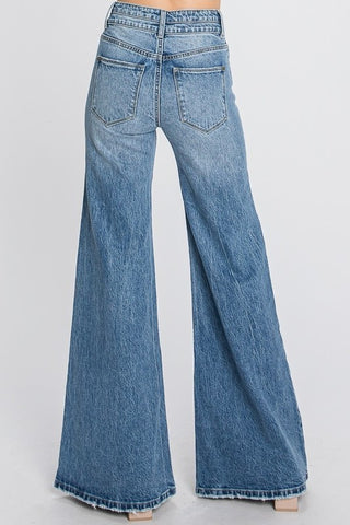 A person is wearing Presley High Rise Comfort Stretch Vintage Wide Leg Jeans by Petra153. The view is from the back, showing two rear pockets and the full-length, flared legs of the jeans against a plain, light background.