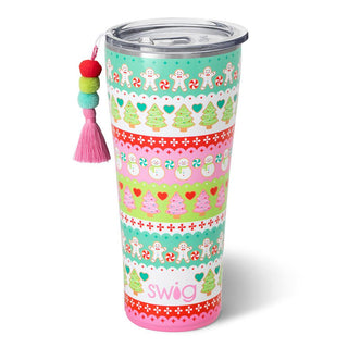 The Cookie Jar Swig 32oz from Western Edge Boutique is an adorable tumbler with a clear lid, decorated with colorful stripes featuring gingerbread men, candy canes, snowmen, and Christmas trees. It includes a tassel charm adorned with multicolored pom-poms on the lid, reminiscent of a festive cookie jar.