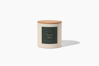 A cream-colored soy wax candle named "Orange Spice" comes with a wooden lid and sports a green label with white text. The label features the brand "Hico Candle Co." and showcases subtle notes of mandarin against a plain white background.