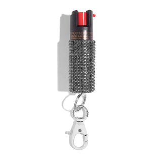 A compact Emergency Pepper Spray Key Ring from BLINGSTING with a textured, rhinestone-covered grip. It features a red trigger on top and is attached to a keychain clip at the bottom. The text "STINGSTREAM PEPPER" is partially visible near the top, affirming its role in women's safety.