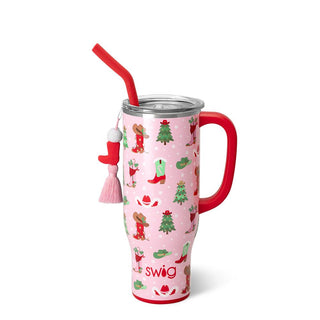 The "Howdy Christmas" tumbler by Western Edge Boutique features a cheerful pink background embellished with gingerbread characters, Christmas trees, and stockings. It comes with a red handle and straw adorned with a pom-pom and tassel charm, all topped off with a clear lid.