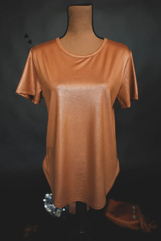 A short-sleeved, bronze-colored, shiny Swanky Faux Leather Cotton Shirt from 2 Fly is displayed on a mannequin against a dark background. The shirt features a round neckline and smooth fabric with a rad leather lux finish.