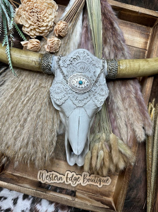 A Jordyn Boho Concho Turquoise Choke Necklace from Western Edge Boutique is artfully displayed against a backdrop of pampas grass and dried flowers. The necklace, featuring intricate lace patterns and a turquoise centerpiece, is set on a rustic wood tray alongside an antique silver plate with the sign "Western Edge Boutique.