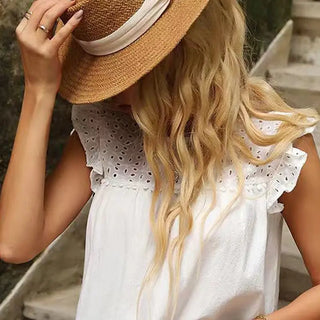 With long, wavy blonde hair, she embodies southern charm in a straw hat and MISS SPARKLING's Southern Belle White Eyelet Tank Top. The elegant lace neckline complements her as she holds the hat brim on a stone staircase, partially turned away from the camera.