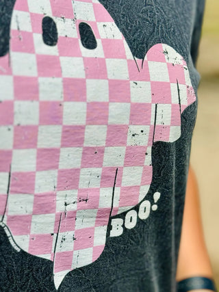 Close-up of a person wearing the Hey Boo Graphic Tee Halloween Graphic Tee by Western Edge Boutique, featuring an adorable pink checkered ghost graphic. The ghost has two black eyes and the word "BOO!" written next to it. A must-have for your wardrobe, the arm of the person is partially visible on the right side.