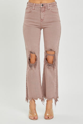 A person wearing the Maris High-Rise Straight Pants by Risen in light pink, featuring large distressed knees and frayed hems. The straight pant style emphasizes the rips at the knees. They are also donning clear, open-toe heels. The image captures only the lower half of the body against a plain background.