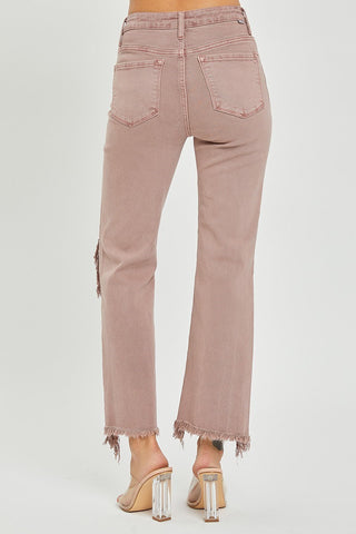 A person wearing Risen's Maris High-Rise Straight Pants in pink, featuring frayed hems and back pockets, paired with clear-heeled sandals. The jeans have slight distressing on one leg. The image shows the person from the back, from the torso down to the feet, set against a plain white background.