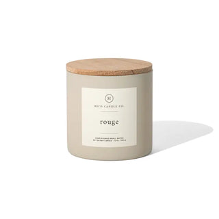 A beige candle jar with a wooden lid and a label that reads "Western Edge Boutique - TOP Seller Candle." This baccarat-inspired candle is hand-poured, small batch, and features a blended soy wax in a 12 oz size. It sits gracefully against a plain white background.