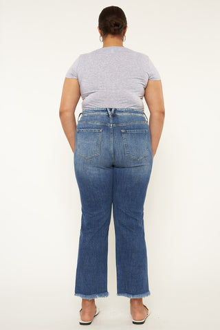 A person is shown from the back wearing a light gray t-shirt and the Kan Can USA Kimber Curvy High Rise Slim Straight Jeans with frayed hems. The person has their hair pulled into a bun and is standing against a plain white background.