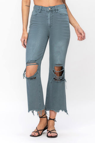 A person wearing Mauli Vintage Crop Flare Jeans by VERVET by Flying Monkey, which are high-waisted and light blue with large, distressed holes at the knees and frayed hems. The jeans are paired with black strappy sandals, and the person is photographed from the waist down against a plain white background.