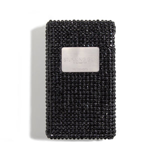 Rectangular black device adorned with numerous small, sparkling black stones, featuring a metallic silver label that reads "Emergency Big Stun Gun by BLINGSTING 950,000 VOLTS." The high-voltage device casts a soft shadow against the white background. Perfect for women's safety.