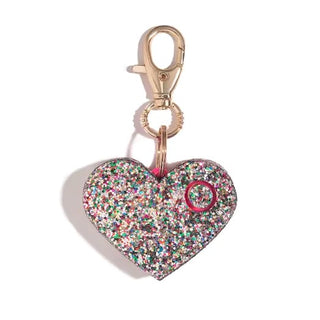 BLINGSTING's Emergency Safety Alarm Key Ring now features a built-in LED safety light within its heart-shaped pendant covered in multicolored glitter. The pendant, adorned with a small circular button, is attached to a gold lobster clasp.