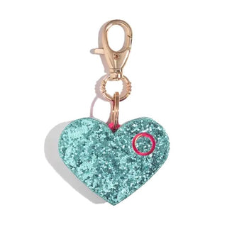 A glittery heart-shaped keychain with a turquoise color is attached to a gold-colored lobster clasp. The heart features a small pink circle detail on the right side and comes from BLINGSTING, a renowned women’s safety brand, notable for including an ear-piercing siren and built-in LED safety light in their Emergency Safety Alarm Key Ring.